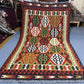Full overhead view of 5x8 ft Turkish Kilim rug with hexagon pattern in red, green, black, and ivory
