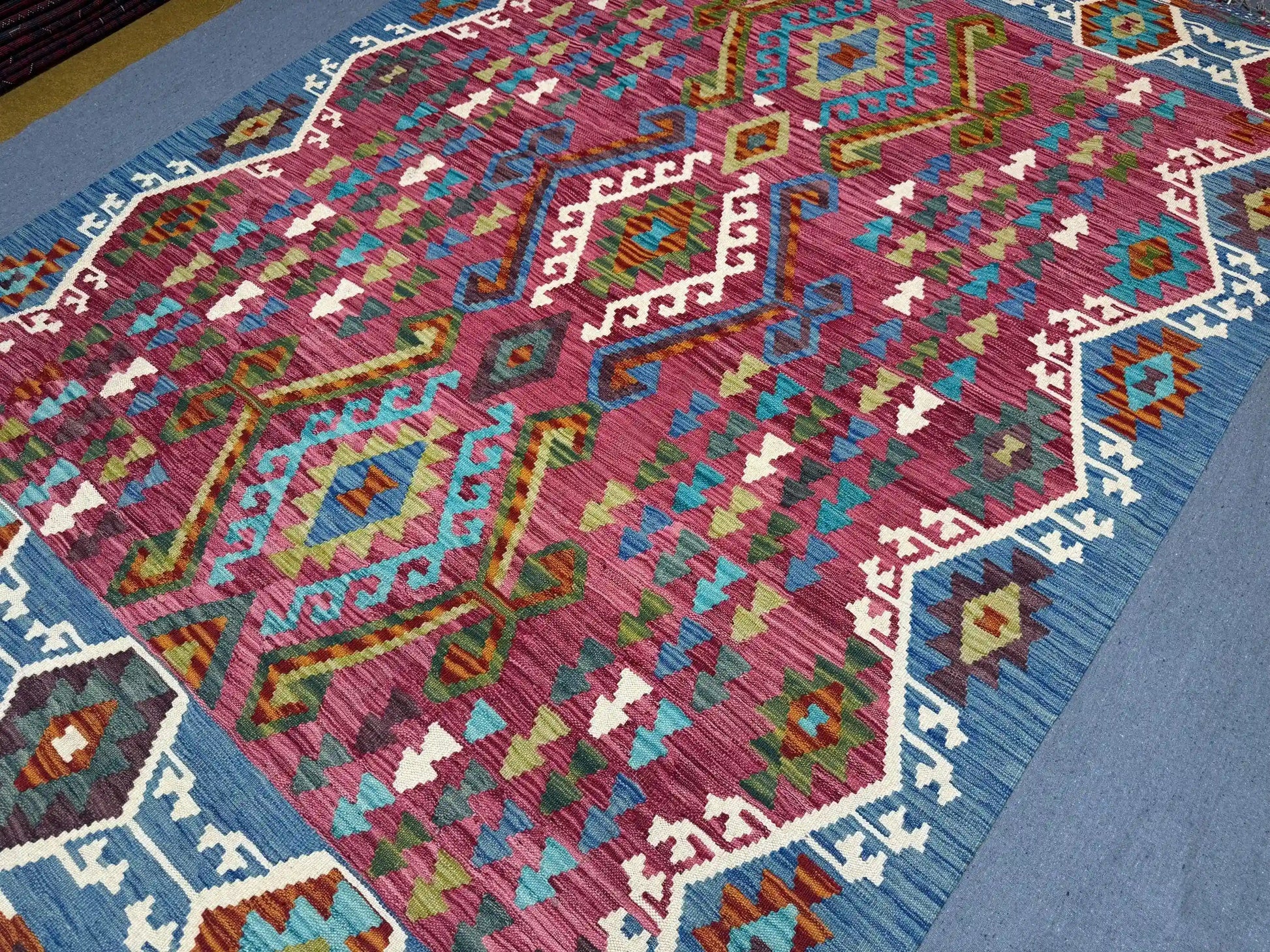  Detailed view of hand-knotted geometric motifs in colorful Kilim rug.