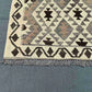 Corner detail of geometric Turkish Kilim rug – earthy tones in wool flatweave with knotted texture.