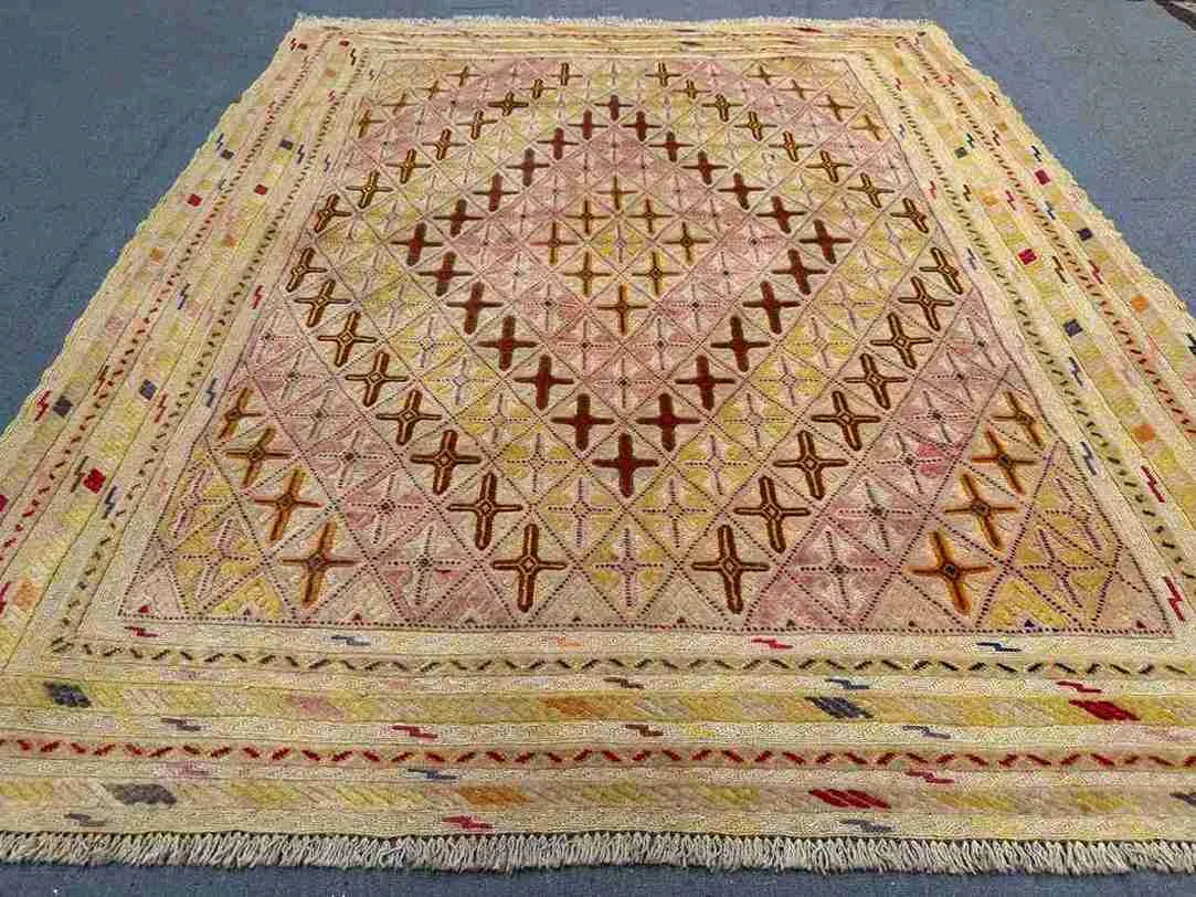 Close-up of geometric tribal pattern in pastel Afghan kilim rug