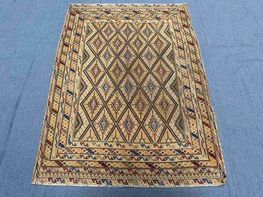 Geometric Afghan tribal rug on floor with red, blue, and beige tonesc