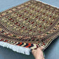 Knotted 5x7 Oriental rug held in hand showing floral pattern and silk texture