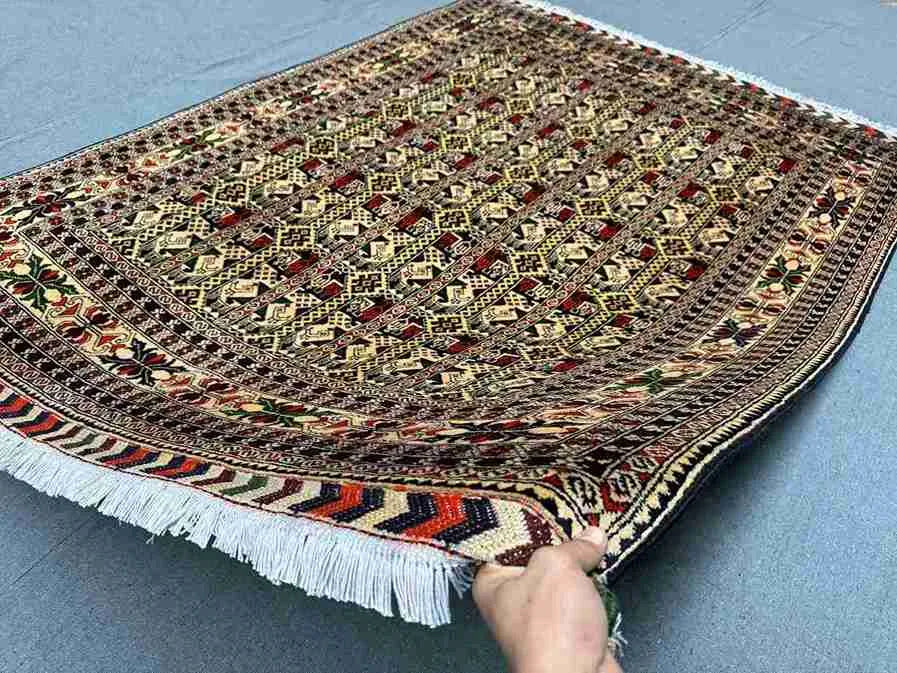 Knotted 5x7 Oriental rug held in hand showing floral pattern and silk texture