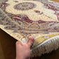 Handmade 5x8 silk rug held in hands showing fine knotted texture