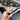 Handwoven black & beige floral rug displayed in hands showing craftsmanship