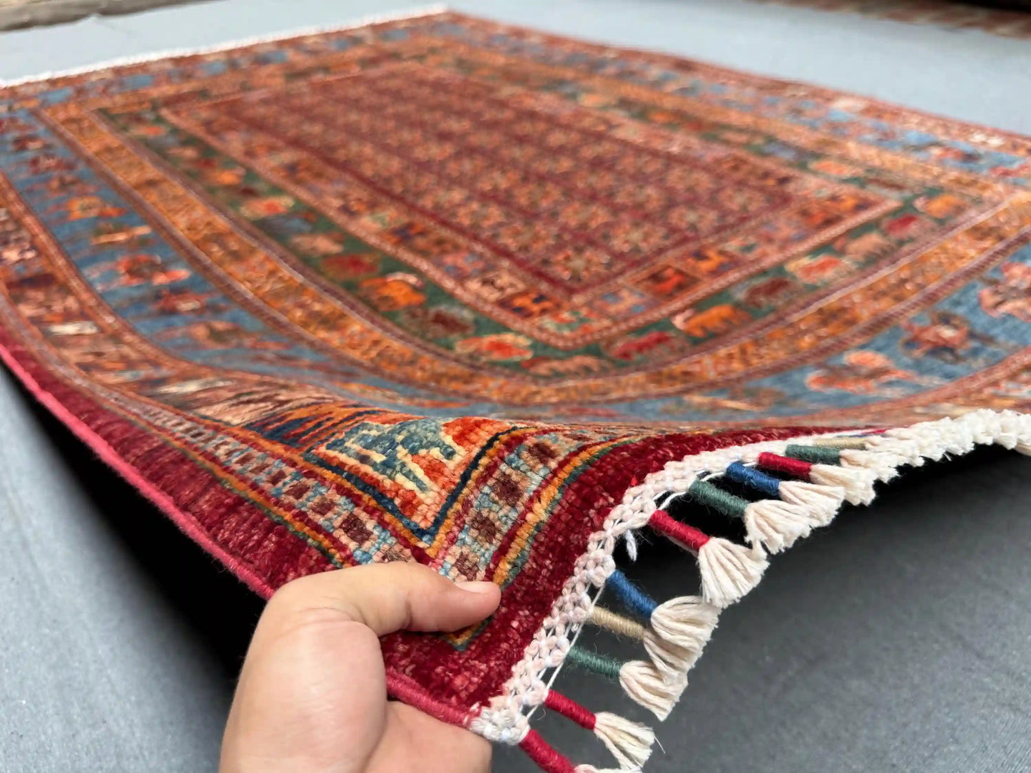 Handmade 6x8 Pazyryk rug held to show softness and weave
