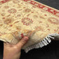 Handmade 5x7 red and cream wool rug shown in hands – Chobi Persian floral design