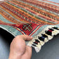 Wool striped Turkish kilim rug in hand, displaying texture and tribal motifs