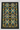 A rectangular area rug with a black background and an intricate, symmetrical floral and geometric pattern in teal, yellow, beige, and gray, laid flat on a light wood floor.