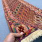 Person holding antique 2.8x9.3 Turkish kilim runner rug – geometric tribal wool carpet