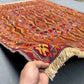 Handwoven 4.9x6.6 Turkish Afghan kilim rug held in hands, showing tribal wool texture and red-orange tones