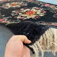 Handmade Karabakh wool rug in hand showing black floral pattern and texture