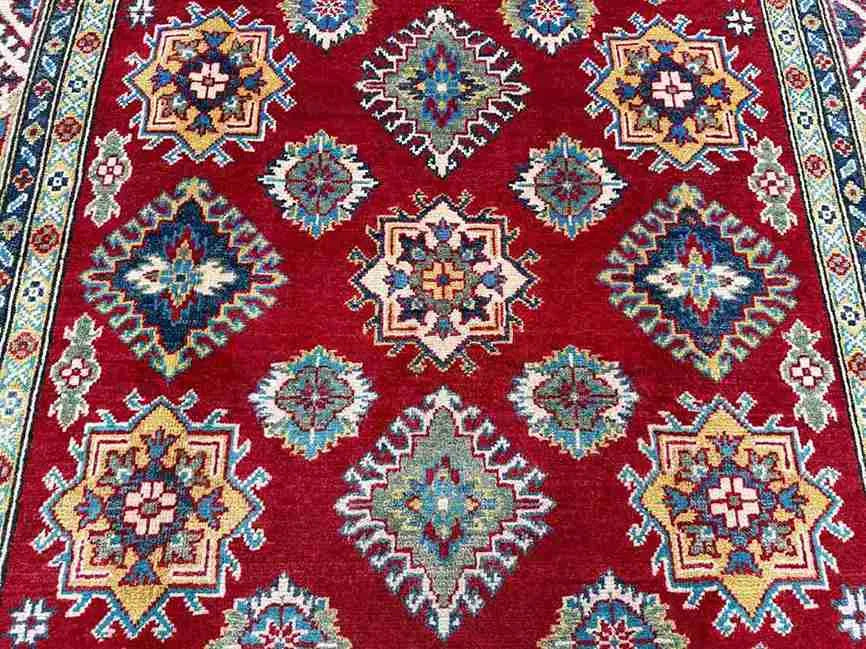 Close-up of floral pattern on red and beige wool Kazakh rug