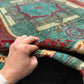 Knotted wool Oriental rug in red and teal displayed in-hand
