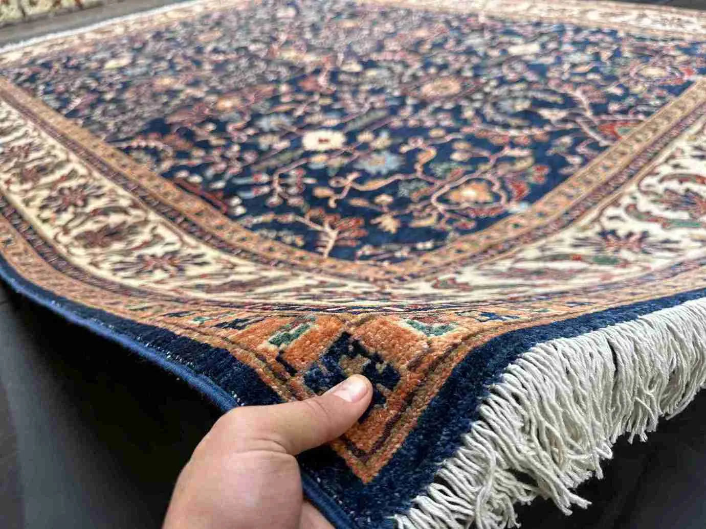 Handmade navy blue Chobi rug shown in hands – front view of wool carpet