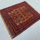 Nomadic oriental wool rug in red and brown displayed on wooden floor