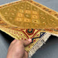 Handmade Afghan kilim rug in hand showing olive and gold wool texture