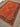 Persian-style orange Chobi rug on floor in cozy bedroom setup