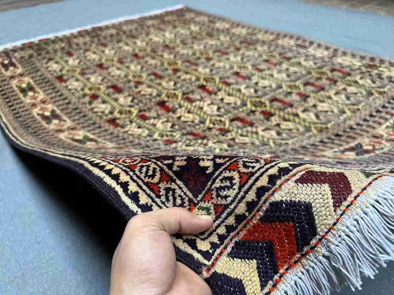 Handmade Oriental wool rug in hand with floral & tribal design