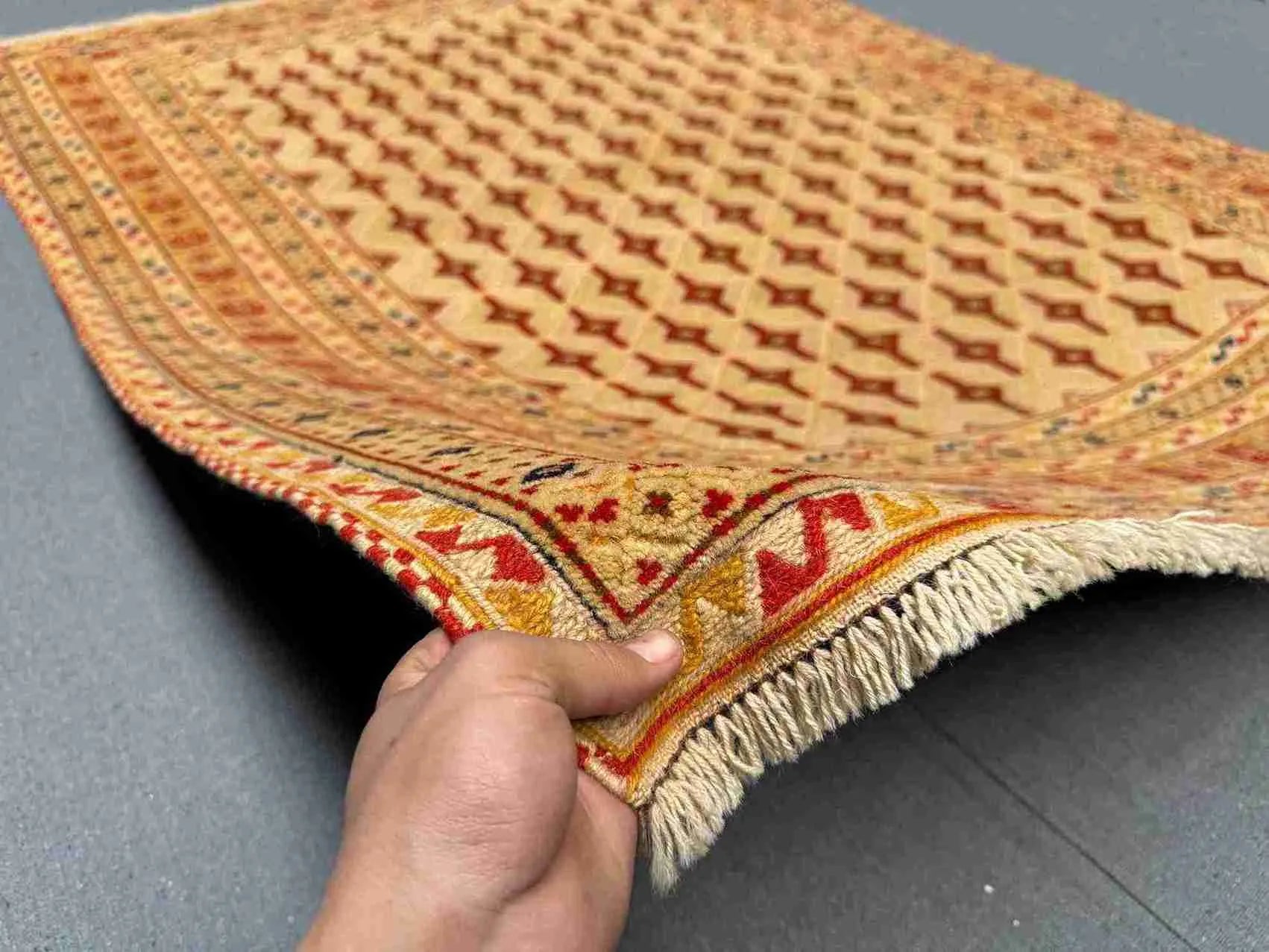 Handmade Persian Afghan rug held in hands showing tribal details