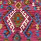 Close-up of tribal geometric patterns on Turkish Kilim rug in pink, blue, and green