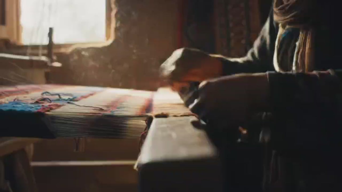 Artisan hands weaving a handmade Persian rug using traditional techniques with colorful wool threads