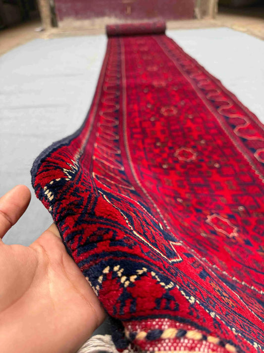 Hand-holding Red Afghan runner rug showing texture and weave