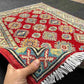 Artisan holding a 5x7 ft red & beige Turkish Kazakh wool rug – knotted luxury carpet