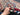 Side view of handmade red and blue wool Turkish rug held in hands
