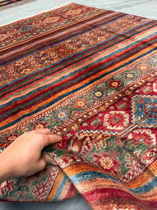 5x8 Red Khorjin Rug held in hands – Handmade Persian wool carpet
