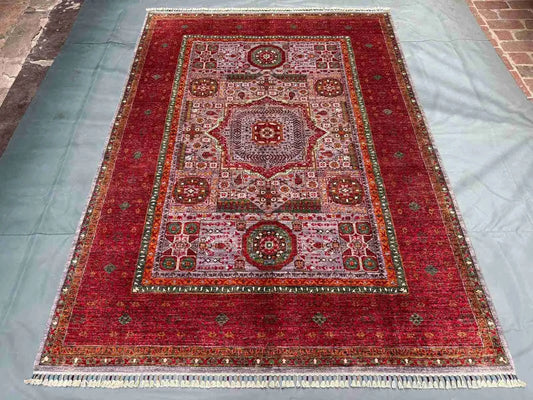 Oriental red rug laid on wooden floor – traditional wool rug