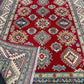 Rolled end of red & beige Turkish Kazakh wool rug
