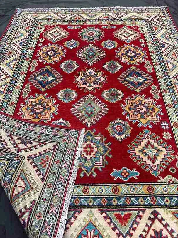 Rolled end of red & beige Turkish Kazakh wool rug