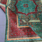 Folded angle view of 6x8 red and teal wool Mamluk rug