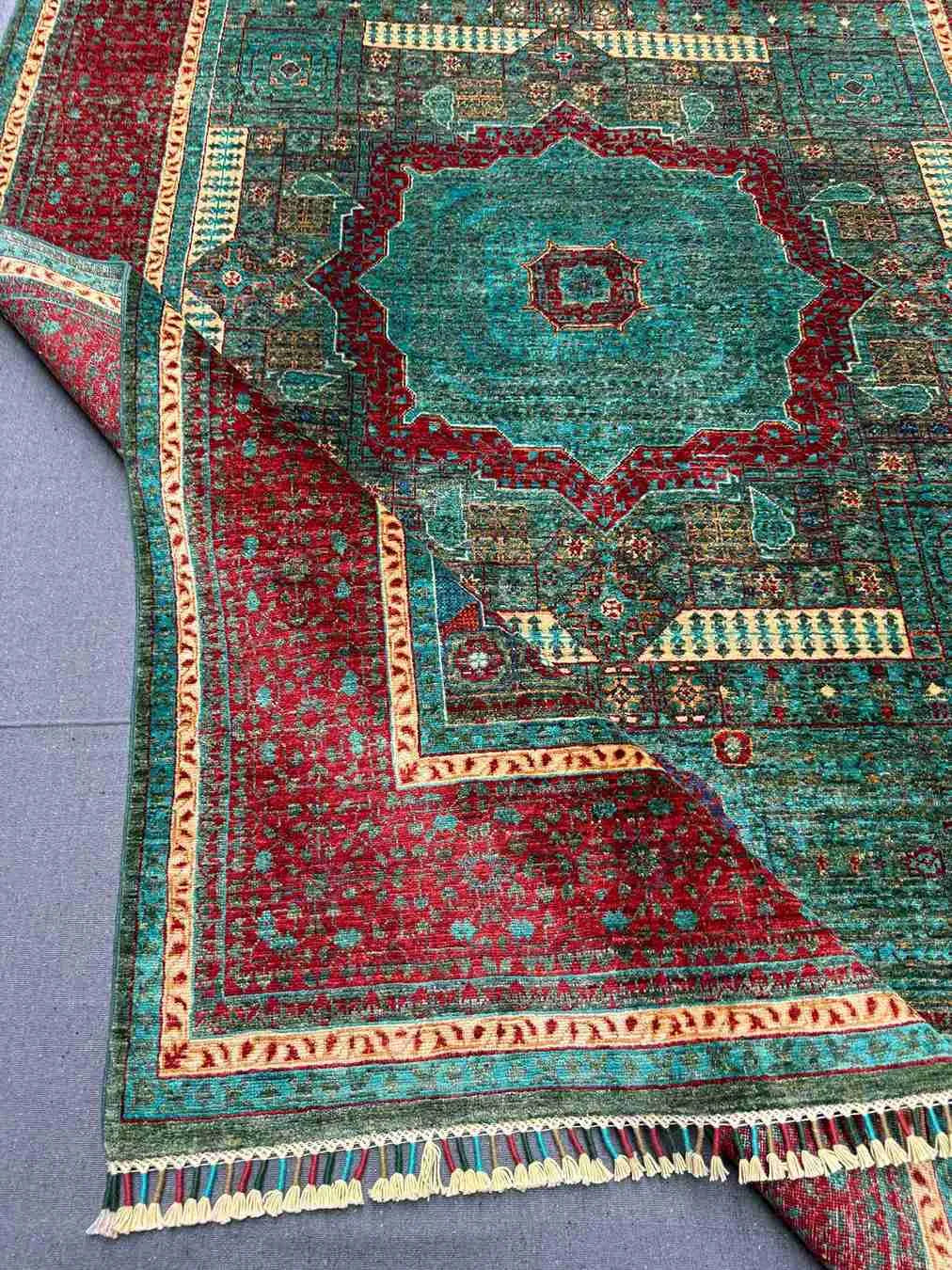 Folded angle view of 6x8 red and teal wool Mamluk rug