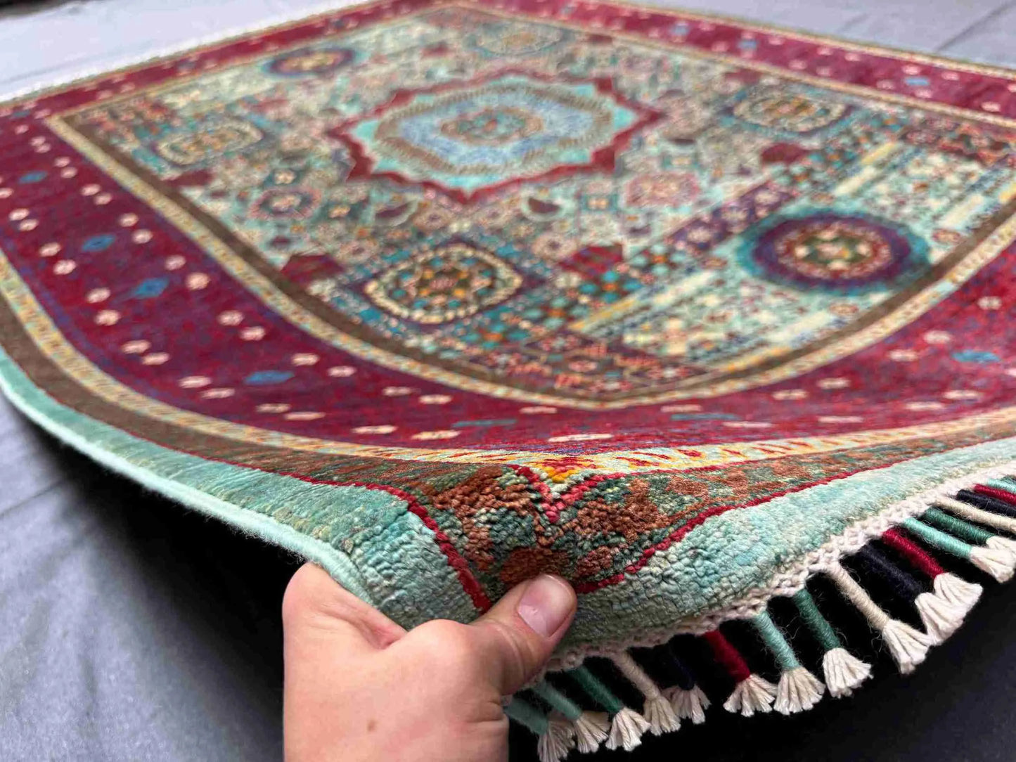 6x8 rustic Turkish Mamluk rug in red and teal held in hand