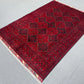 Side view of deep red Afghan wool rug on floor