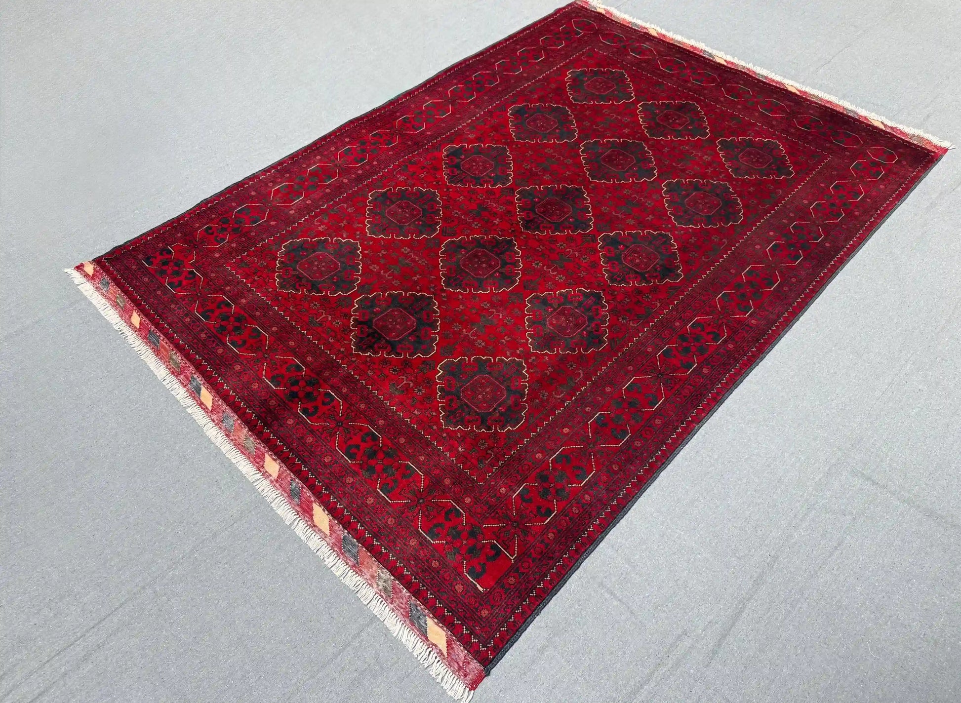 Side view of deep red Afghan wool rug on floor