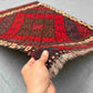 Handwoven small Afghan red Kilim rug held in hands – front view showing geometric wool flatweave.