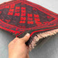 Handmade small red Kilim rug held in hands – geometric wool flatweave with traditional knotted design.