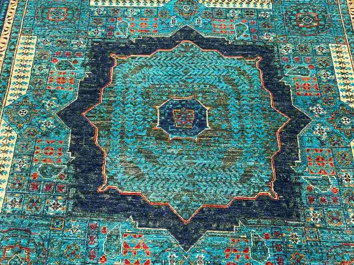 Close-up texture of hand-knotted wool Mamluk rug in green and gold