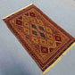 Traditional Afghan wool rug on floor with geometric tribal patterns