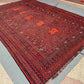 Handmade red and black Turkish Kilim rug styled on wooden floor – tribal geometric wool flatweave.