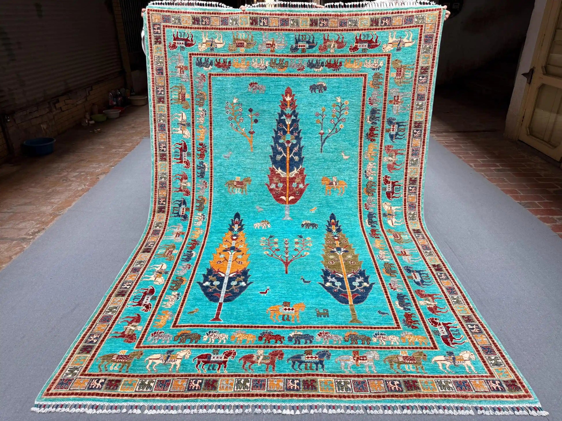 Full view of Tree of Life wool carpet in turquoise blue on floor