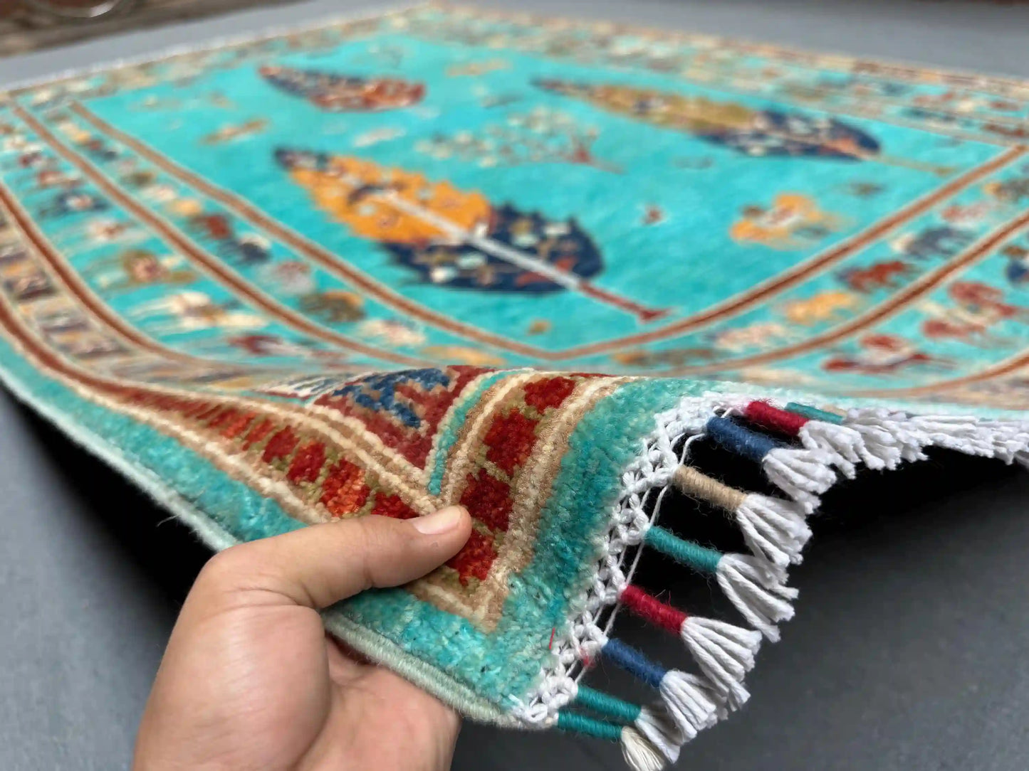 6x8 handmade Tree of Life wool rug in hands, turquoise blue