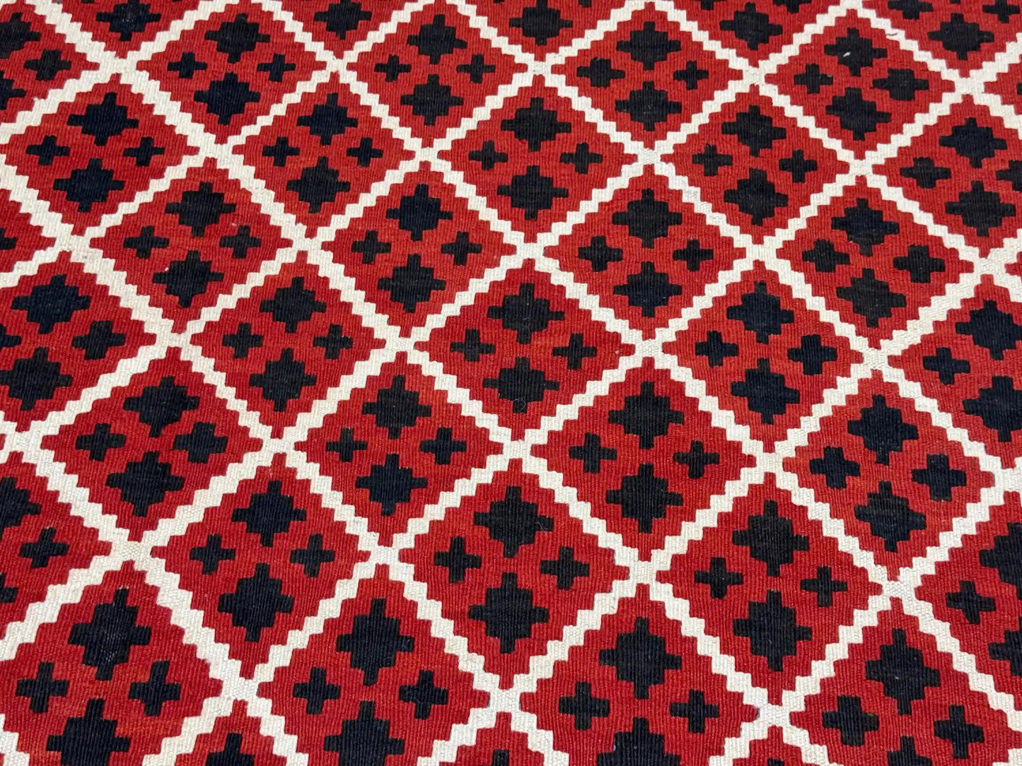Detailed pattern from corner of boho tribal kilim rug – red wool