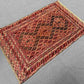 Top view of red tribal Afghan rug on wooden floor
