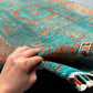 Hand-knotted 6x8 turquoise Mamluk wool rug held for close texture view