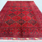 Handmade red wool tribal rug styled in a bedroom