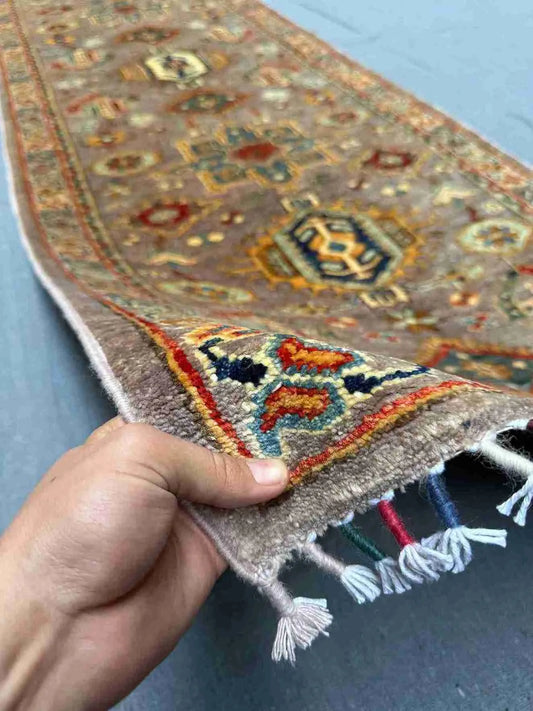 Handmade Waziri runner rug held in hand showing tribal Afghan design